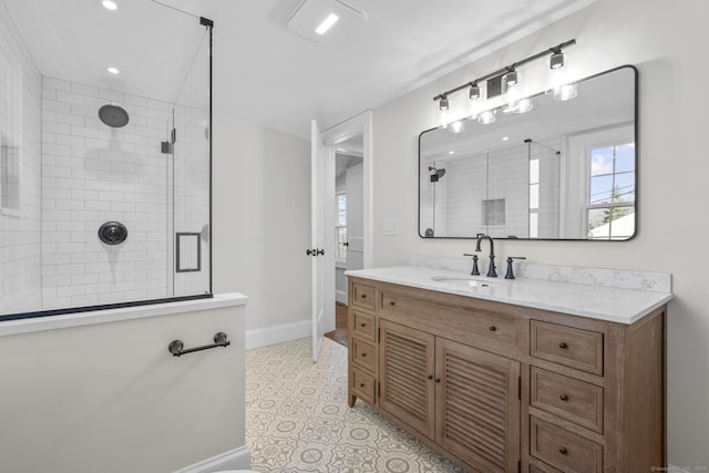 full bathroom featuring recessed lighting, tiled shower, vanity, and baseboards