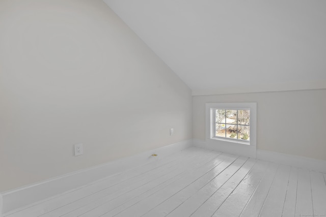 spare room with hardwood / wood-style floors, lofted ceiling, and baseboards