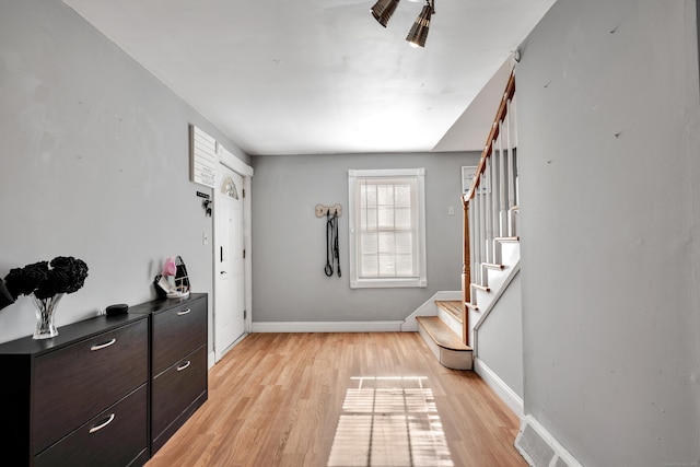 entryway with stairway, visible vents, light wood-type flooring, and baseboards