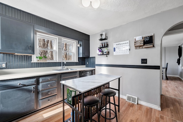 kitchen featuring visible vents, a sink, light countertops, a textured ceiling, and light wood-type flooring