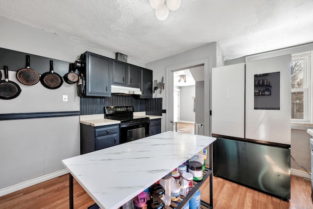 kitchen featuring freestanding refrigerator, electric range, light wood-type flooring, and under cabinet range hood