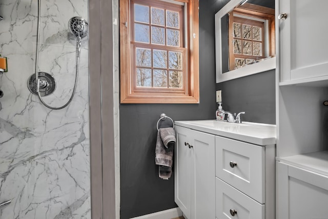 full bath featuring a marble finish shower and vanity