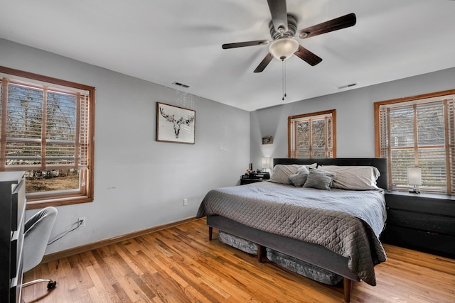 bedroom with a ceiling fan, wood finished floors, visible vents, and baseboards