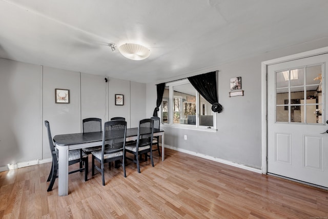 dining space featuring baseboards and light wood-style flooring