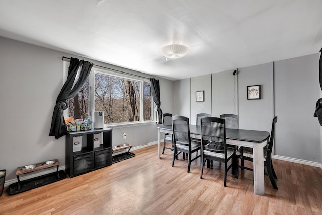 dining space with baseboards and wood finished floors