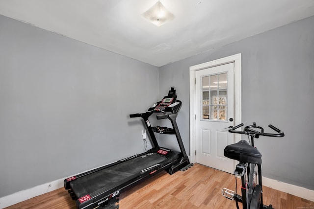 exercise area with baseboards and light wood finished floors