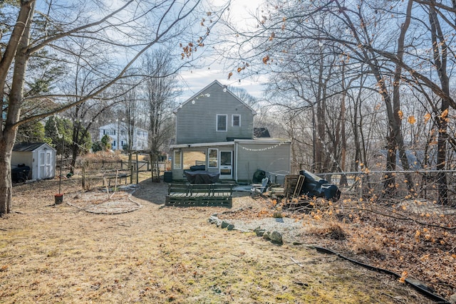 rear view of property featuring a wooden deck, fence, an outdoor structure, and a shed