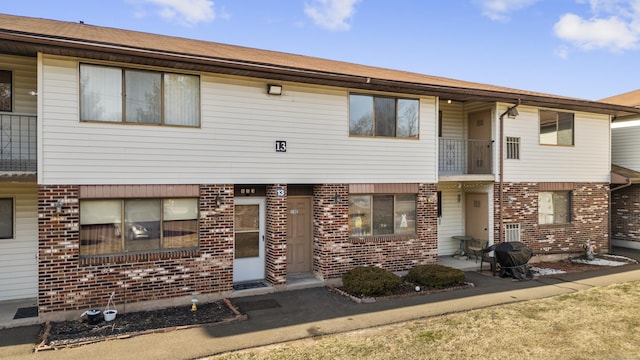 townhome / multi-family property featuring a balcony and brick siding