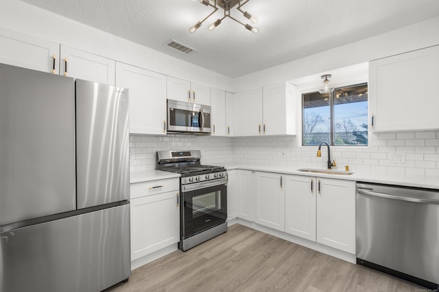 kitchen with visible vents, light wood-type flooring, a sink, appliances with stainless steel finishes, and light countertops