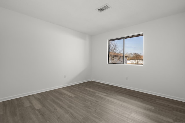 unfurnished room with visible vents, baseboards, and dark wood-style flooring