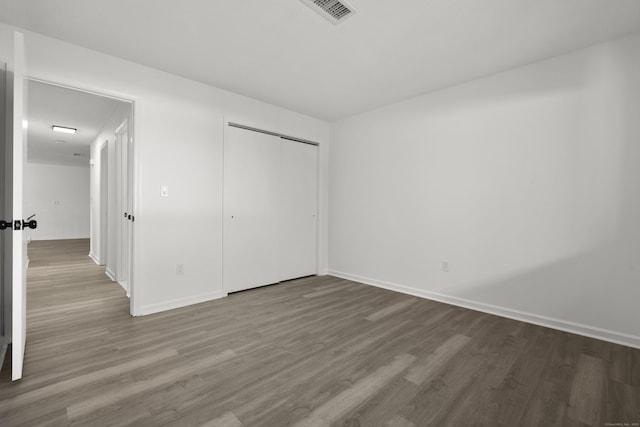 unfurnished bedroom featuring visible vents, baseboards, and wood finished floors