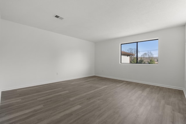 unfurnished room with visible vents, baseboards, and dark wood-type flooring