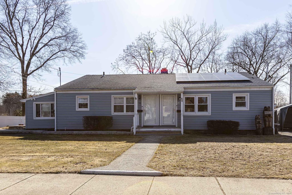 single story home with a front lawn, a chimney, roof mounted solar panels, and roof with shingles