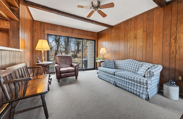 living room with beam ceiling, wood walls, carpet floors, and ceiling fan