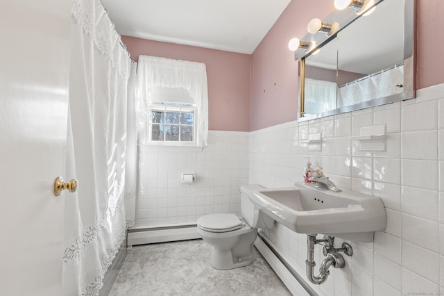 bathroom with baseboard heating, wainscoting, toilet, and tile walls