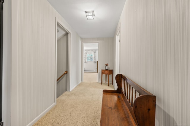 hall with an upstairs landing, carpet flooring, and a baseboard heating unit