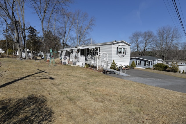 manufactured / mobile home with covered porch, driveway, and a front lawn