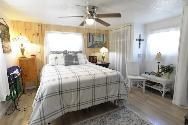 bedroom with multiple windows, wood finished floors, and wood walls