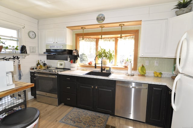 kitchen featuring a sink, under cabinet range hood, white cabinetry, appliances with stainless steel finishes, and dark cabinets