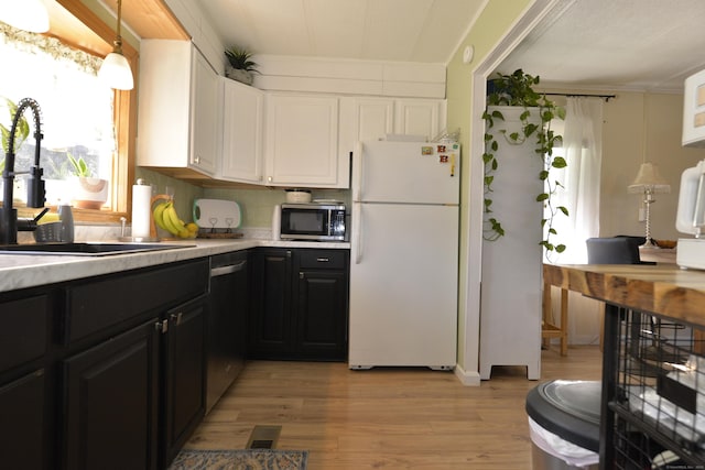 kitchen with a sink, stainless steel appliances, light countertops, white cabinets, and light wood-type flooring