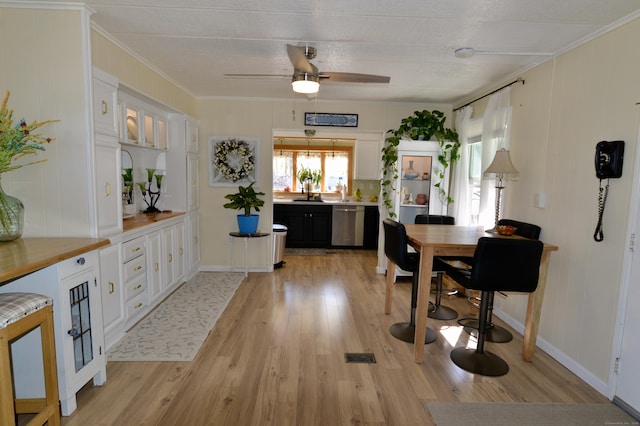 dining area with ornamental molding, light wood-type flooring, and ceiling fan