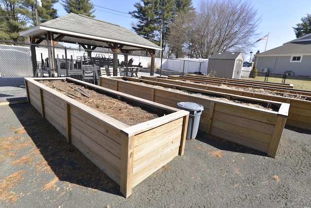 view of patio featuring fence, a gazebo, a garden, an outbuilding, and a storage unit