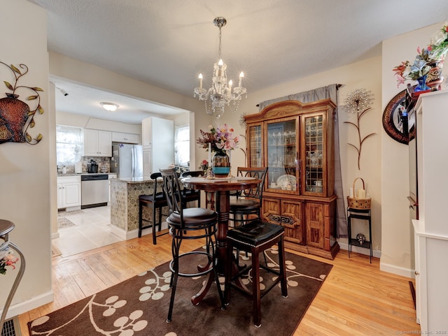 dining area with a chandelier, baseboards, and light wood-style flooring