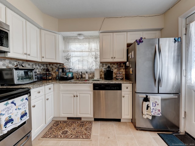 kitchen featuring a sink, decorative backsplash, appliances with stainless steel finishes, and white cabinets