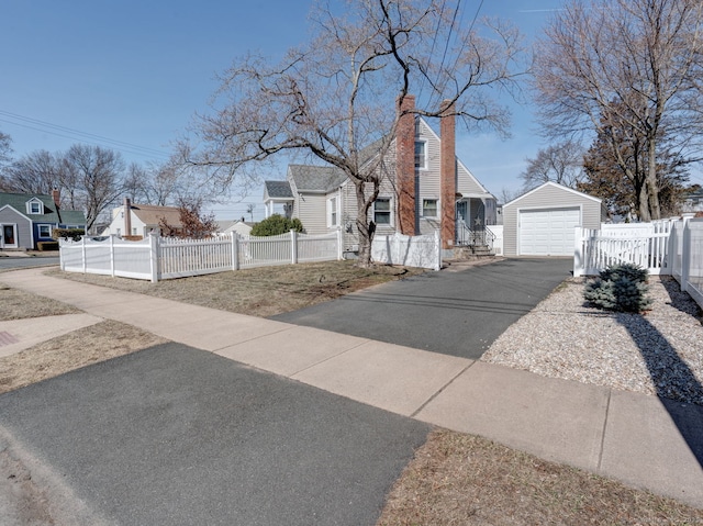 exterior space with an outdoor structure, a garage, driveway, and a fenced front yard