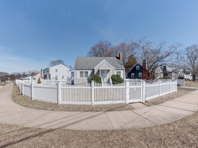 bungalow-style house featuring a residential view, a fenced front yard, and a chimney