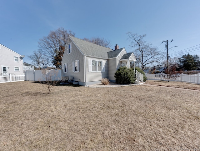 view of side of property featuring a shingled roof, a lawn, a fenced backyard, and a chimney