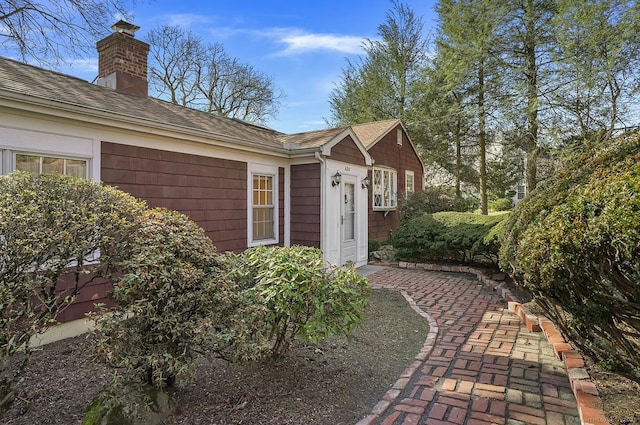 view of property exterior with a chimney and a shingled roof