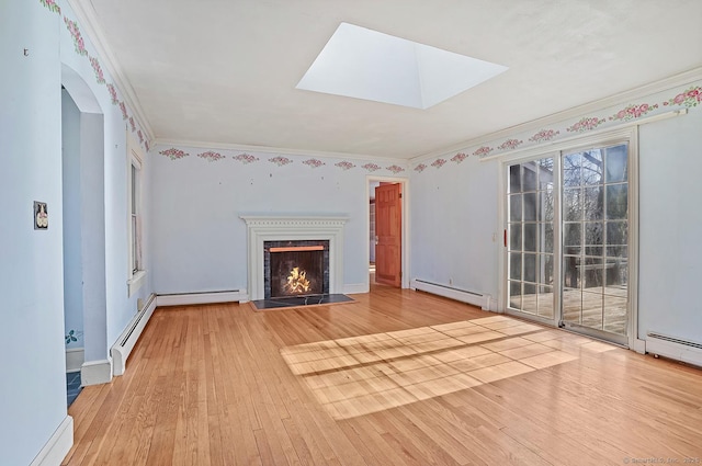 unfurnished living room featuring a fireplace with flush hearth, hardwood / wood-style floors, a skylight, crown molding, and baseboard heating