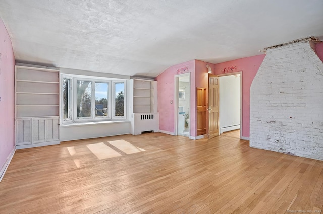 unfurnished living room featuring wood finished floors, radiator, brick wall, a baseboard radiator, and lofted ceiling