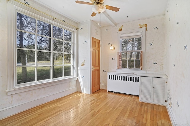 interior space with light wood finished floors, baseboards, radiator heating unit, and a ceiling fan