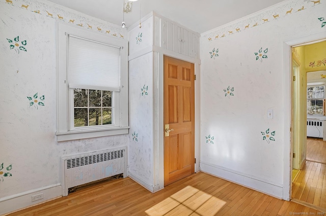 foyer featuring wallpapered walls, radiator, light wood-style floors, and baseboards