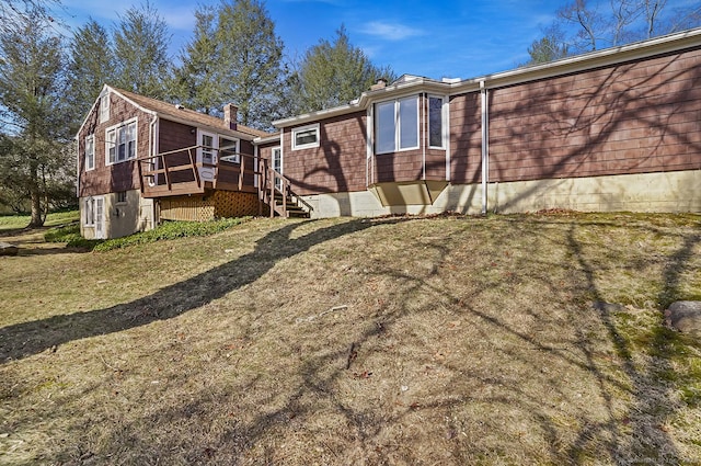 back of property featuring a lawn, a deck, and a chimney