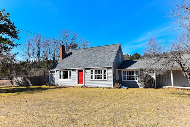 view of front facade with a chimney, a shingled roof, a front yard, and fence