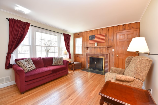 living area featuring baseboards, visible vents, a fireplace, ornamental molding, and hardwood / wood-style flooring