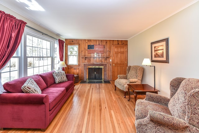 living area with crown molding, a brick fireplace, and light wood-type flooring