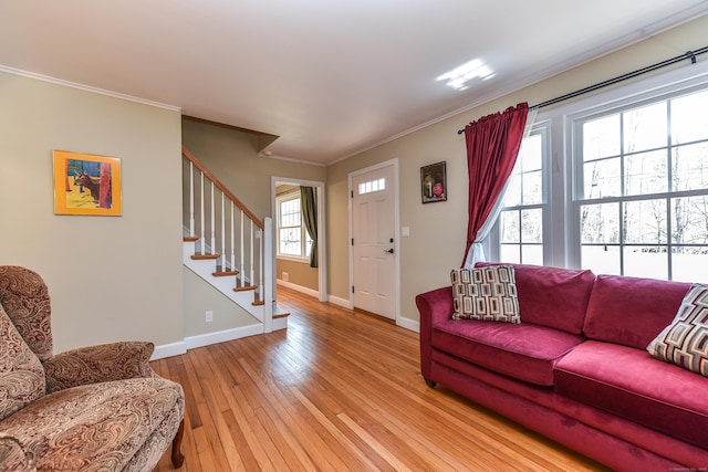 living room with stairway, baseboards, crown molding, and light wood finished floors