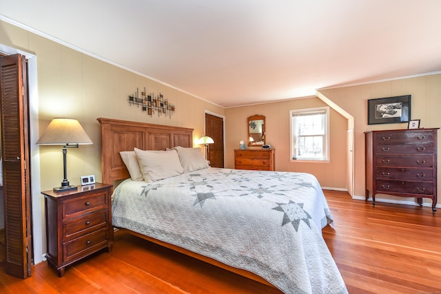 bedroom with wood finished floors and crown molding