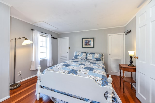 bedroom with baseboards, attic access, wood finished floors, and ornamental molding