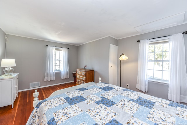 bedroom with visible vents, wood finished floors, crown molding, baseboards, and attic access