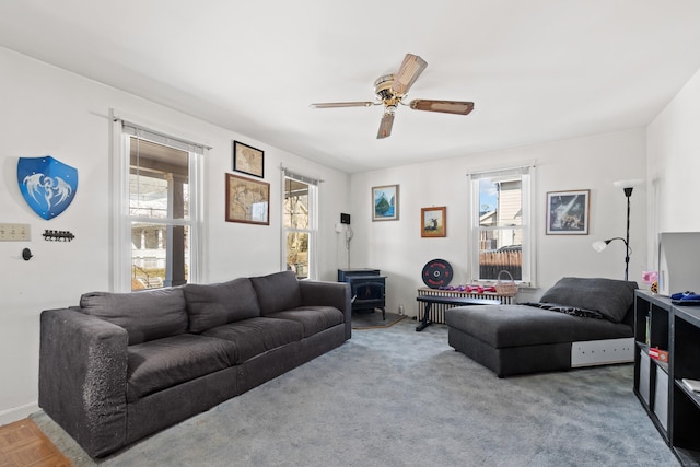 living room featuring a wood stove and a ceiling fan