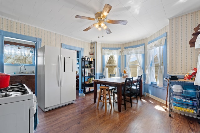 dining area with ornamental molding, wood finished floors, wallpapered walls, baseboards, and ceiling fan