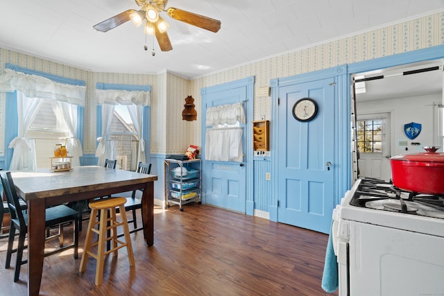 dining room with wallpapered walls, crown molding, wood finished floors, and a ceiling fan