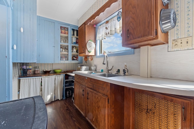 kitchen with tasteful backsplash, brown cabinetry, light countertops, dark wood-style floors, and a sink