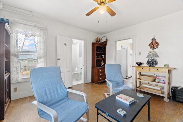 living area featuring baseboards and a ceiling fan