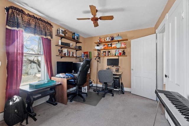 carpeted office space featuring baseboards and a ceiling fan